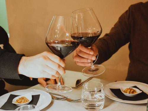 two people holding glasses of red wine at a table at Cora Hotels Leon d'Oro in CastellʼArquato