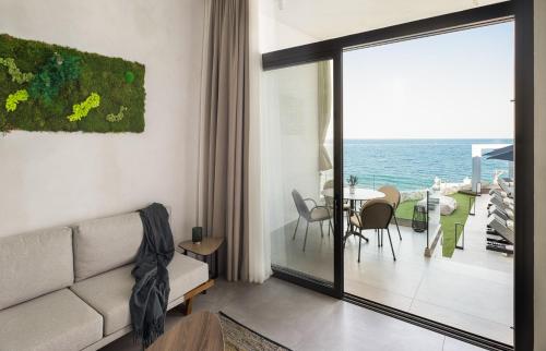 a living room with a couch and a view of the ocean at Akrotiri Olympus Luxury Suites - Adults Only in Plaka Litochorou