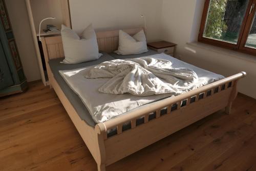 uma cama com lençóis brancos e almofadas num quarto em Am Hirschberg em Bad Hindelang