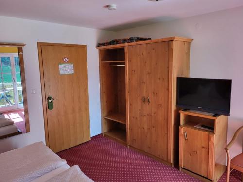 una camera da letto con TV e armadio in legno di Gästehaus Schwarz a Prien am Chiemsee