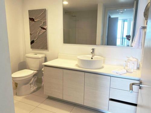 a bathroom with a sink and a toilet and a mirror at Scenic Miami Beach Oasis - Full Kitchen -08A in Hallandale Beach