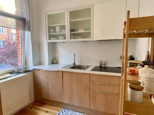 eine Küche mit weißen Schränken, einem Waschbecken und einem Fenster in der Unterkunft Les Valcaprimontoises … en ville ! in Lüttich