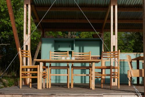 een houten tafel en stoelen onder een prieel bij Agricola Ombra - Tents in nature in Laiatico