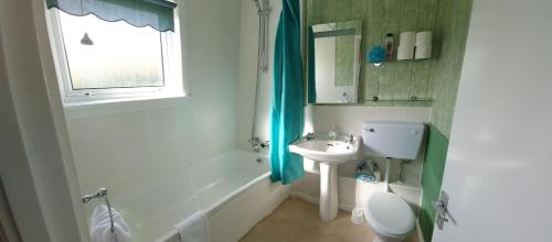 a bathroom with a sink and a toilet and a window at Parcview #1 in Stornoway