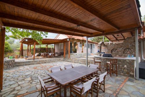 an outdoor patio with a wooden table and chairs at Petrochori Beach House in Voidokilia