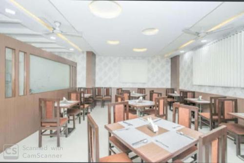 a dining room with tables and chairs and a whiteboard at Western Keys Hotel in Bangalore