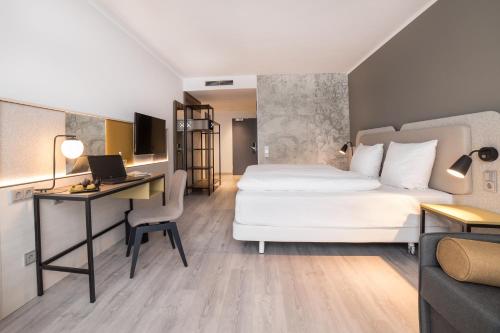 a hotel room with a bed and a desk with a computer at SCOTTY & PAUL Hotel Deggendorf in Deggendorf
