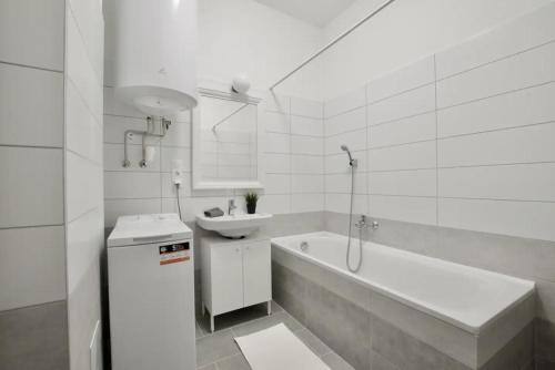 a white bathroom with a sink and a bath tub at Family Apartments by Hi5 - Zamardi in Zamárdi