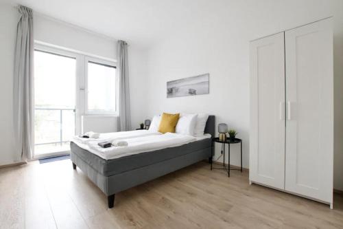 a white bedroom with a bed and a large window at Family Apartments by Hi5 - Zamardi in Zamárdi