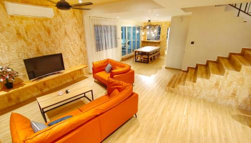 a living room with an orange couch and a television at JB City Villa (Private Pool) in Johor Bahru
