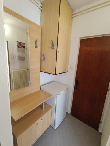 a small kitchen with a white refrigerator and wooden cabinets at Rooms Rita in Cres