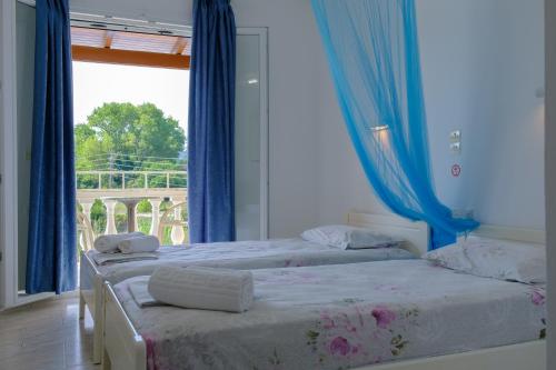 twee bedden in een kamer met blauwe gordijnen en een raam bij Bardis Hotel in Arillas