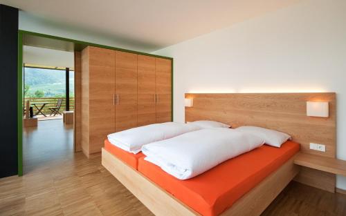 a bedroom with a bed with white pillows and an orange blanket at Appartements Kortscherhof in Silandro