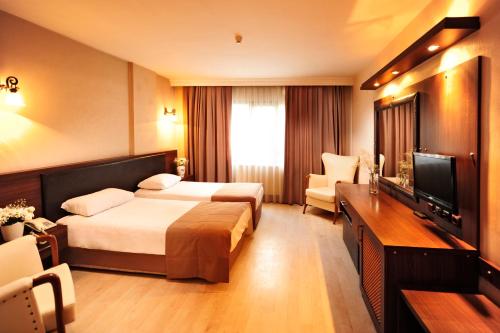 イズミールにあるÜstün Hotel Alsancakのベッド2台、薄型テレビが備わるホテルルームです。