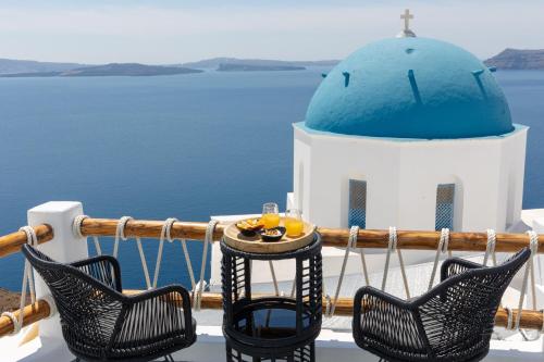 a table and chairs on a balcony with a blue dome at Luxus VIP Suites in Oia