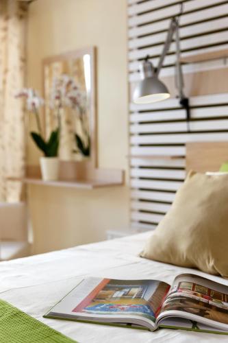 a book sitting on top of a bed with a lamp at Svea Hotel in Rhodes Town