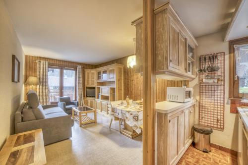 eine Küche und ein Wohnzimmer mit einem Sofa und einem Tisch in der Unterkunft Studio cabine Le Charvet in Le Grand-Bornand