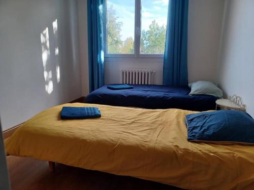 - une chambre avec 2 lits avec des draps bleus et une fenêtre dans l'établissement Maison chaleureuse, gîte pour famille, amis, ouvriers..., à Château-Gontier
