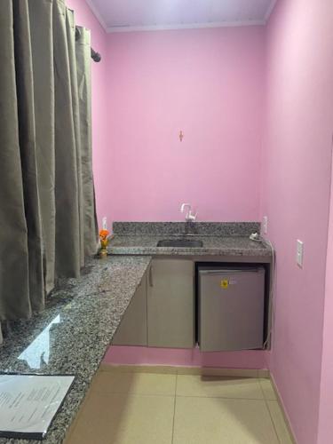 uma casa de banho com um lavatório e uma parede rosa em Pousada Mercosul em Alegrete
