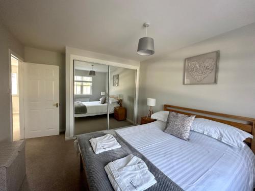 a bedroom with a large bed and a mirror at Denburn Cottage, East Neuk of Fife in Colinsburgh