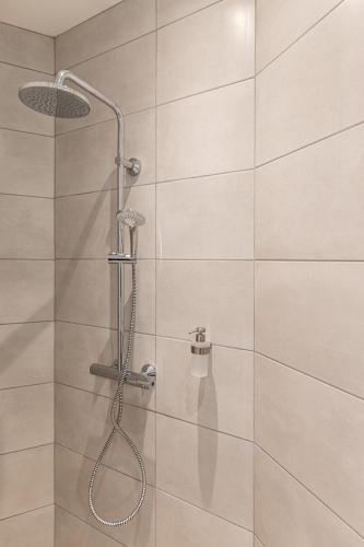 une douche avec pommeau de douche dans une salle de bain dans l'établissement L'éclat - Résidence Hestia, à Saint-Étienne