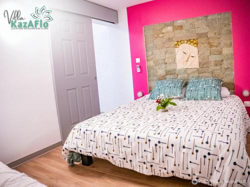um quarto com uma cama e uma parede rosa em La villa KazAFlo Piscine, jacuzzi, SPA, brasero em Saint-Joseph