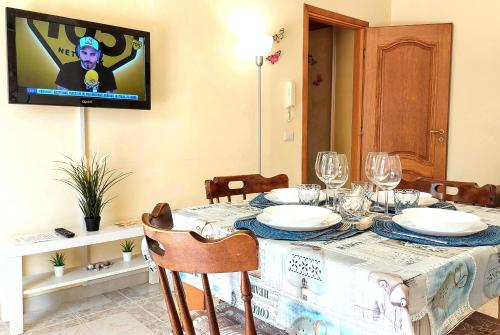 uma sala de jantar com uma mesa e uma televisão na parede em Myrea House em Avola