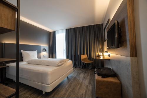 a hotel room with a bed and a desk at SCOTTY & PAUL Hotel Deggendorf in Deggendorf