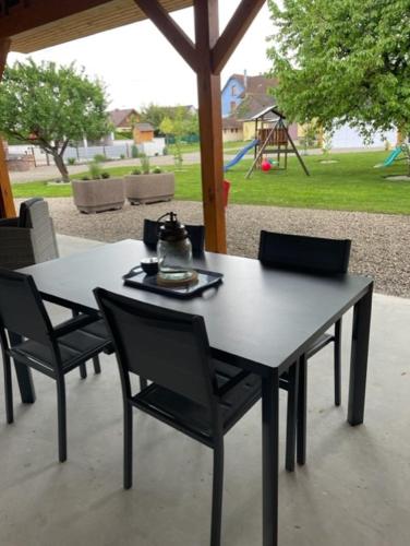 une table noire et des chaises avec une aire de jeux en arrière-plan dans l'établissement Gîte Cosy L'Ecrin du Ried PROCHE EUROPA-PARK, à Artolsheim