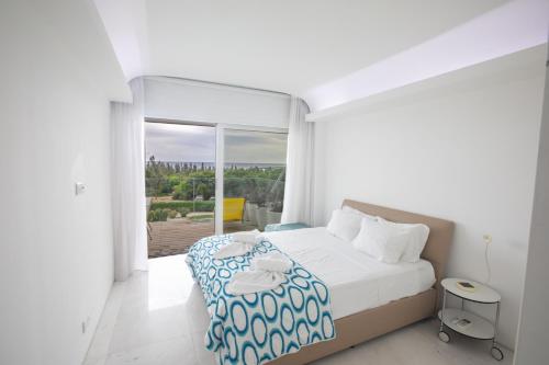 a white bedroom with a bed and a large window at Thalassa Luxury Apartment in Protaras