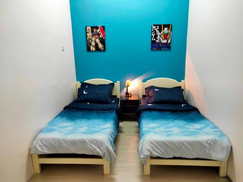 two beds in a room with blue walls at SALAM Homestay D'Gerik in Gerik