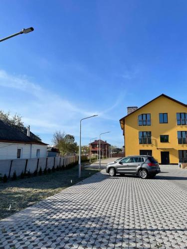 a car parked on a street next to a yellow building at Yellow apartments in Boryspilʼ