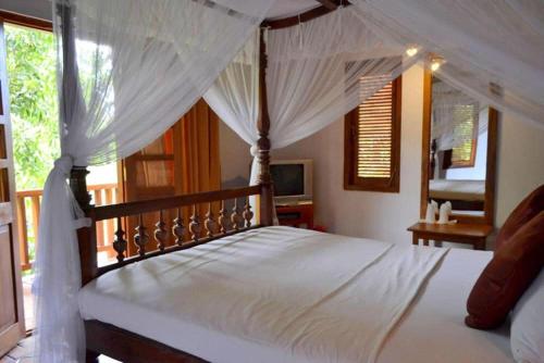 a bedroom with a white bed with a canopy at Landa Holiday House in Belihuloya