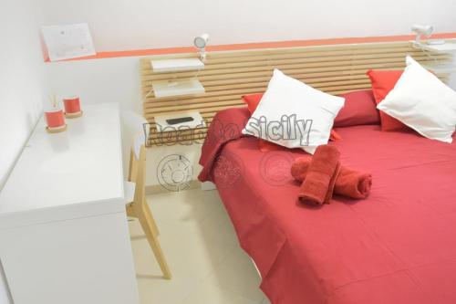 a red bed with a teddy bear sitting on it at Mizar - Road to Sicily in Marina di Ragusa