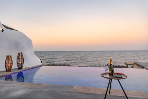 una mesa con una copa de vino junto al océano en Casa di Mare Luxury Villas en Imerovigli