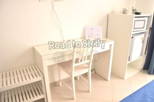 a white desk with a chair next to a refrigerator at Mizar - Road to Sicily in Marina di Ragusa