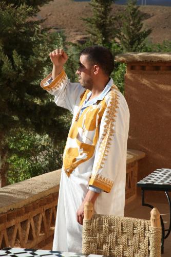 a man dressed in white and gold standing on a balcony at Dar Mezyana Dades in Aït Idaïr
