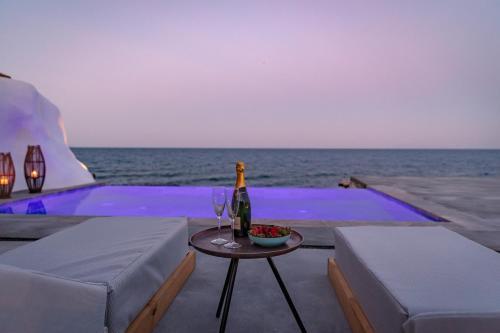 a bottle of wine sitting on a table next to the ocean at Casa di Mare Luxury Villas in Imerovigli