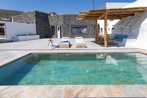 a swimming pool with two chairs and a house at Casa di Mare Luxury Villas in Imerovigli