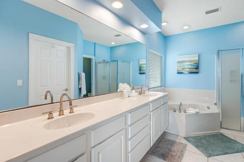 a blue bathroom with two sinks and a tub at Beachy Dreams in Pensacola Beach