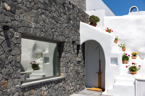 a facade of a house with white walls and flowers at Casa di Mare Luxury Villas in Imerovigli