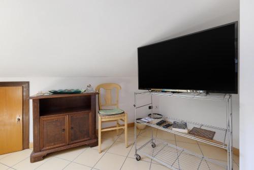 a living room with a flat screen tv and a chair at Mansarda di Ponente in Caorle