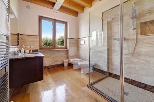 a bathroom with a glass shower and a toilet at Villa Sellemond in Lazise
