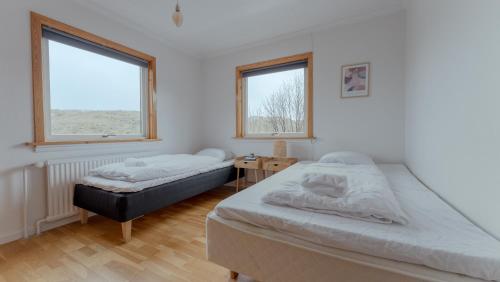 a bedroom with two beds and two windows at Unique Location - Bodanes - Hoydalar - 6 BR Villa in Tórshavn