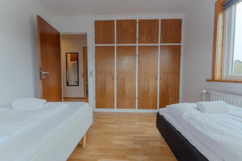 two beds in a room with wooden cabinets at Unique Location - Bodanes - Hoydalar - 6 BR Villa in Tórshavn