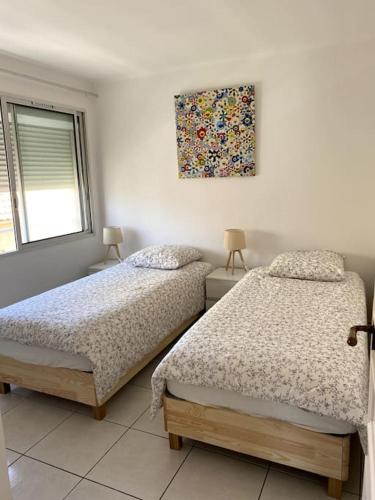 une chambre avec deux lits et un tableau au mur dans l'établissement Bel Appartement en front de mer -Palavas les Flots, à Palavas-les-Flots