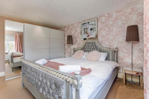 una camera da letto con un grande letto con carta da parati rosa di The Gardens - Stunning Farmhouse a York