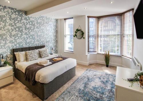 a bedroom with a large bed and some windows at Beautiful Three Bed Flat in Nottingham City Centre in Nottingham