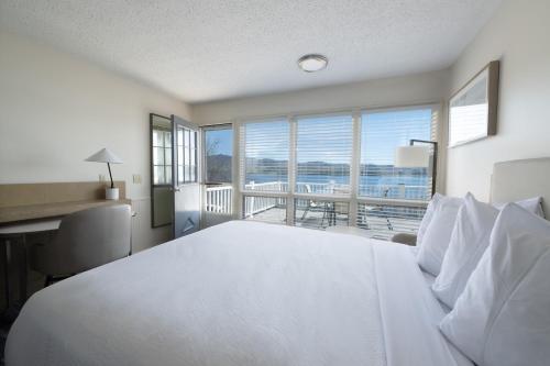 a bedroom with a bed and a desk and a balcony at Depe Dene Lakeside Resort in Lake George