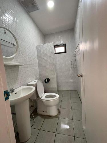 a white bathroom with a toilet and a sink at บ้านกลางนาพูลวิลล่า น่าน in Nan